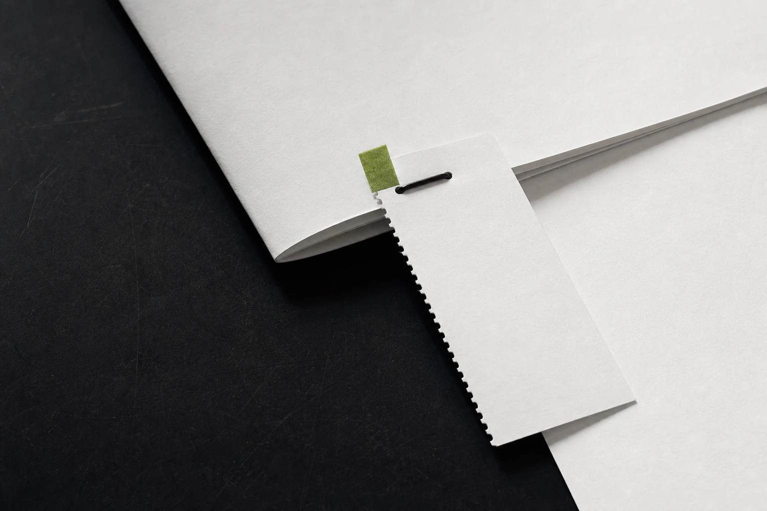A blank perforated paper receipt physically stitched to its folded source sheet beside a small green proof tab