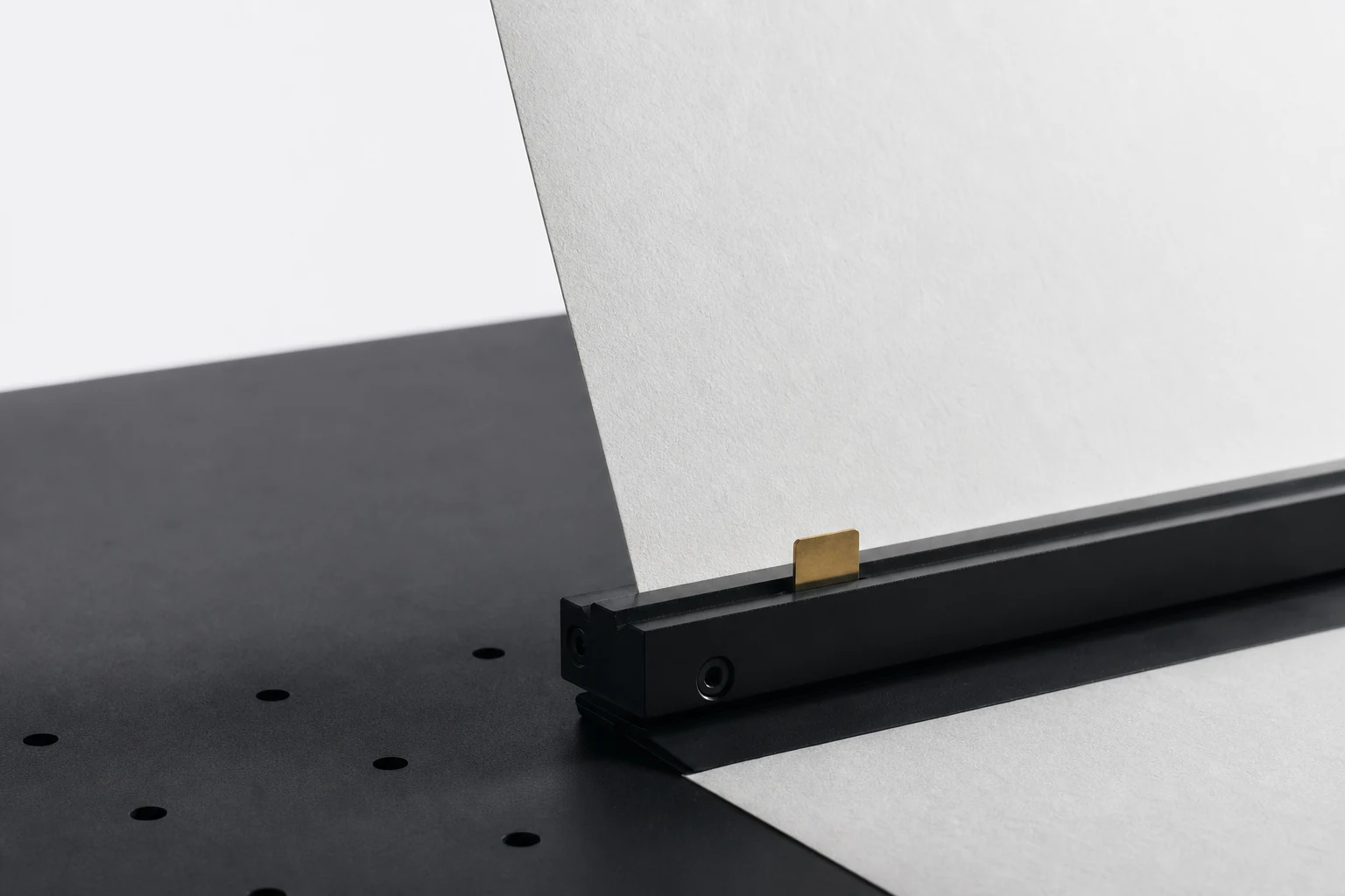 A porcelain paper edge held upright by a black decision rail with one gold authority tab at the stop boundary