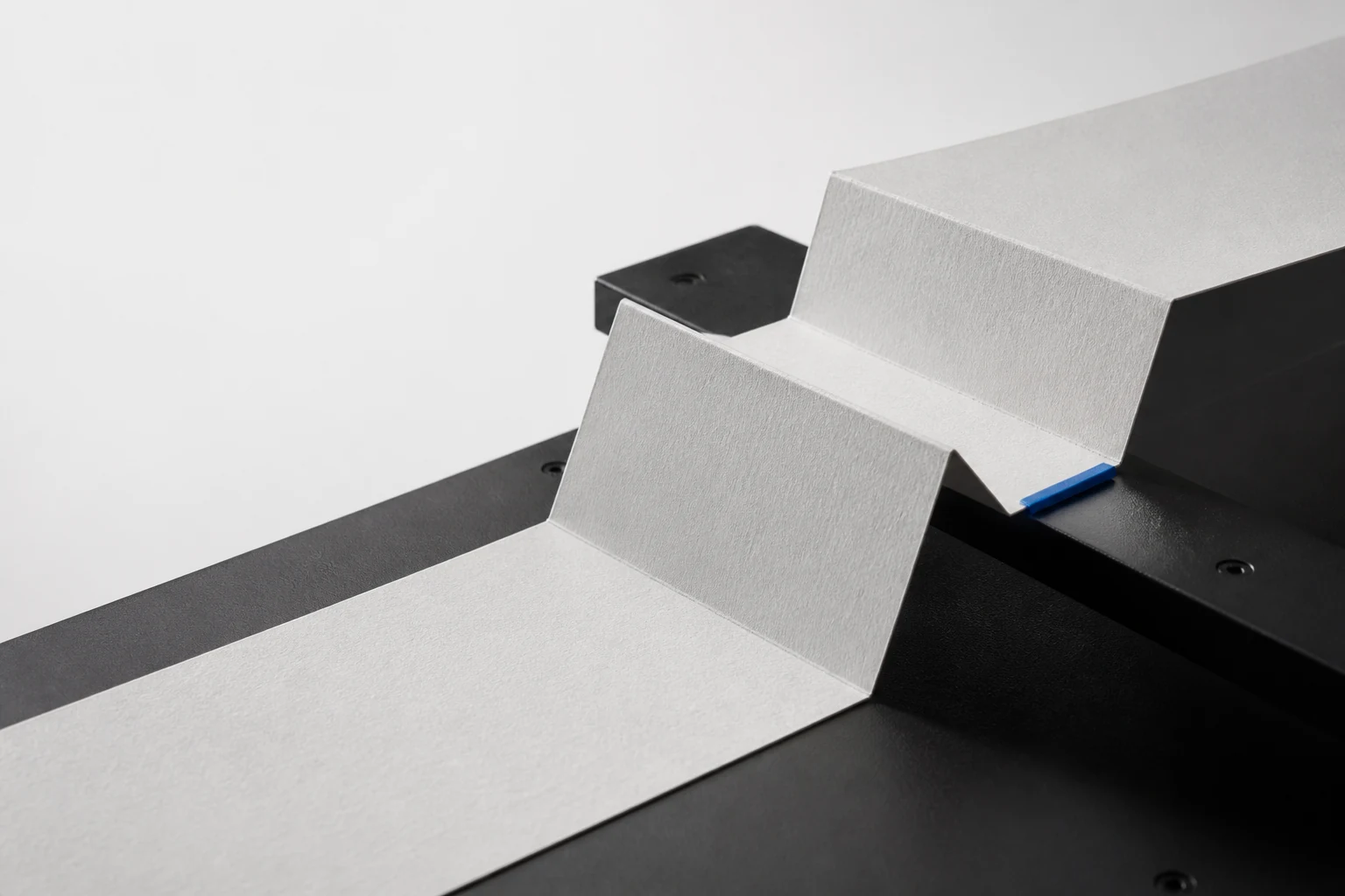 A porcelain paper route crossing two hard folds and a black transfer bridge before settling at a cobalt handoff tab