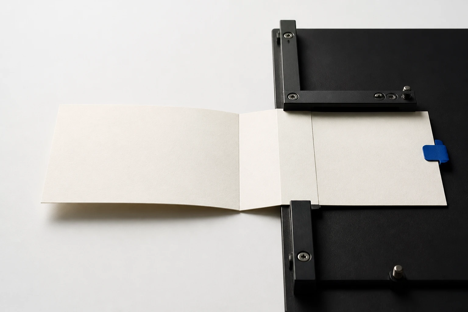 A blank porcelain source sheet crosses scored folds and a black control bridge before ending at one cobalt operating-route tab