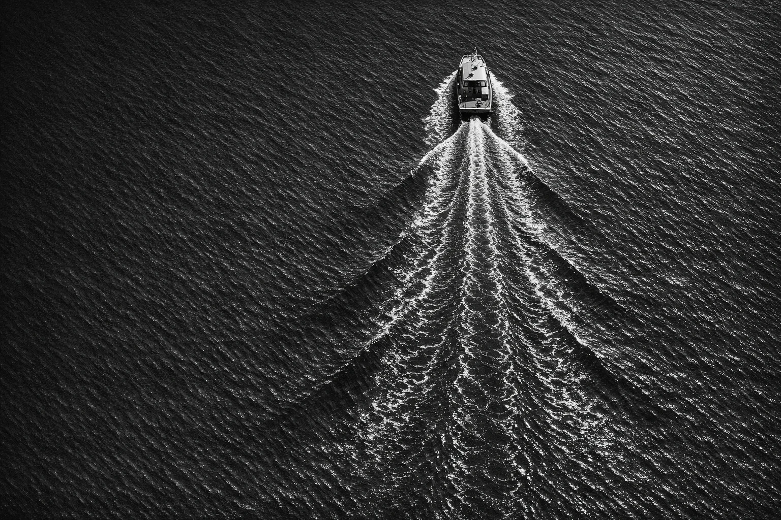 Aerial black-and-white view of a controlled wake tracing a path through water